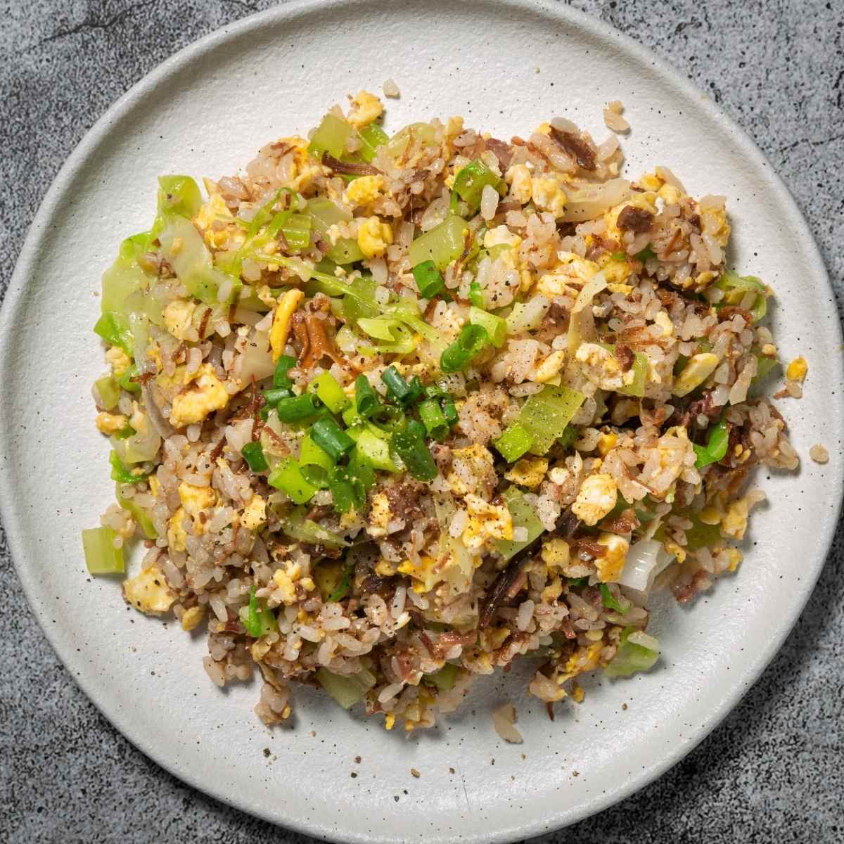 fried rice with vegetables with green onion and herbs on a plate