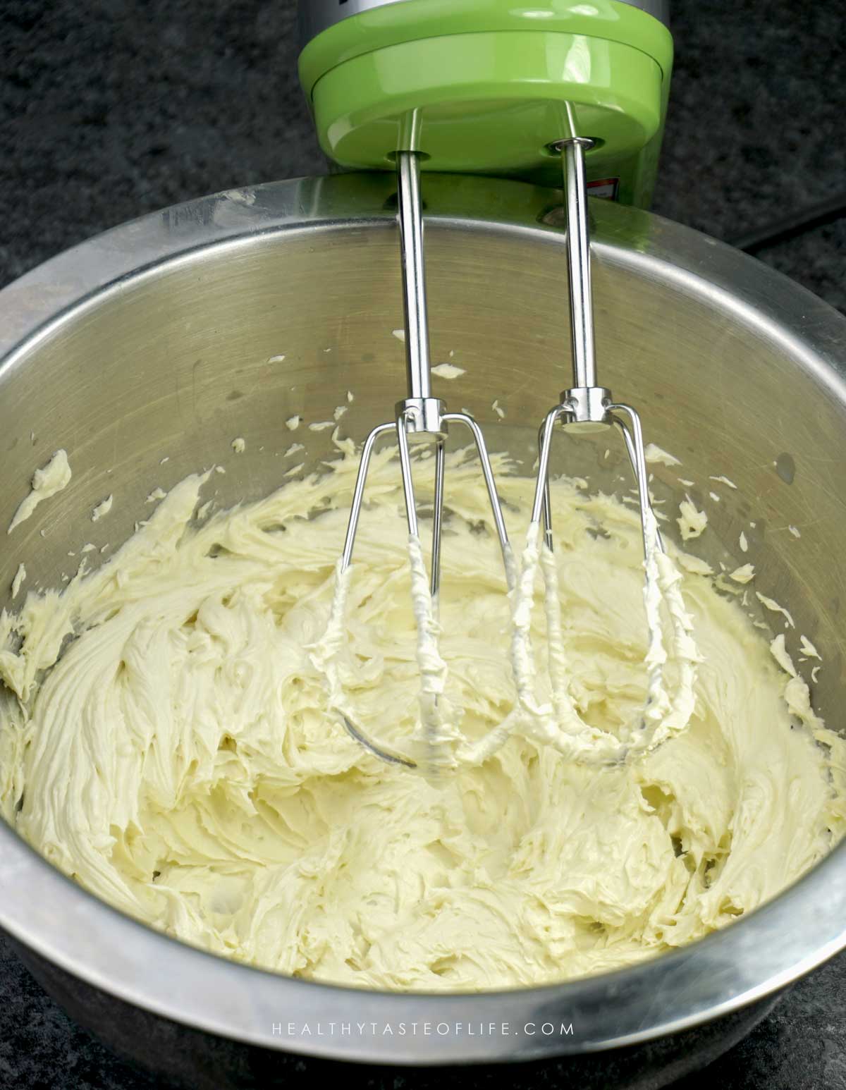 Whipping the mango butter with a hand mixer for a fluffy texture,