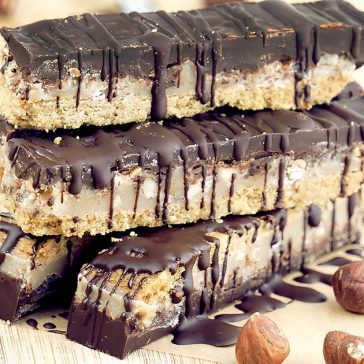 Homemade Chocolate Caramel Hazelnut Bars with a gluten free shortbread crust, dairy free chewy caramel, crunchy hazelnuts and a rich coating of high quality chocolate. These homemade candy bars are also vegan, soy free and refined sugar free.