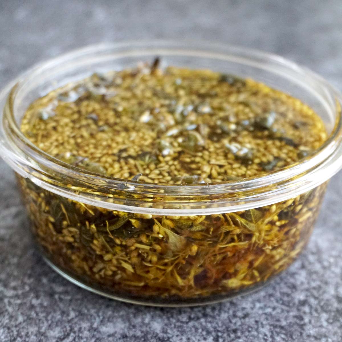 infused oil with dry herbs calendula, yarrow and plantain in a glass container