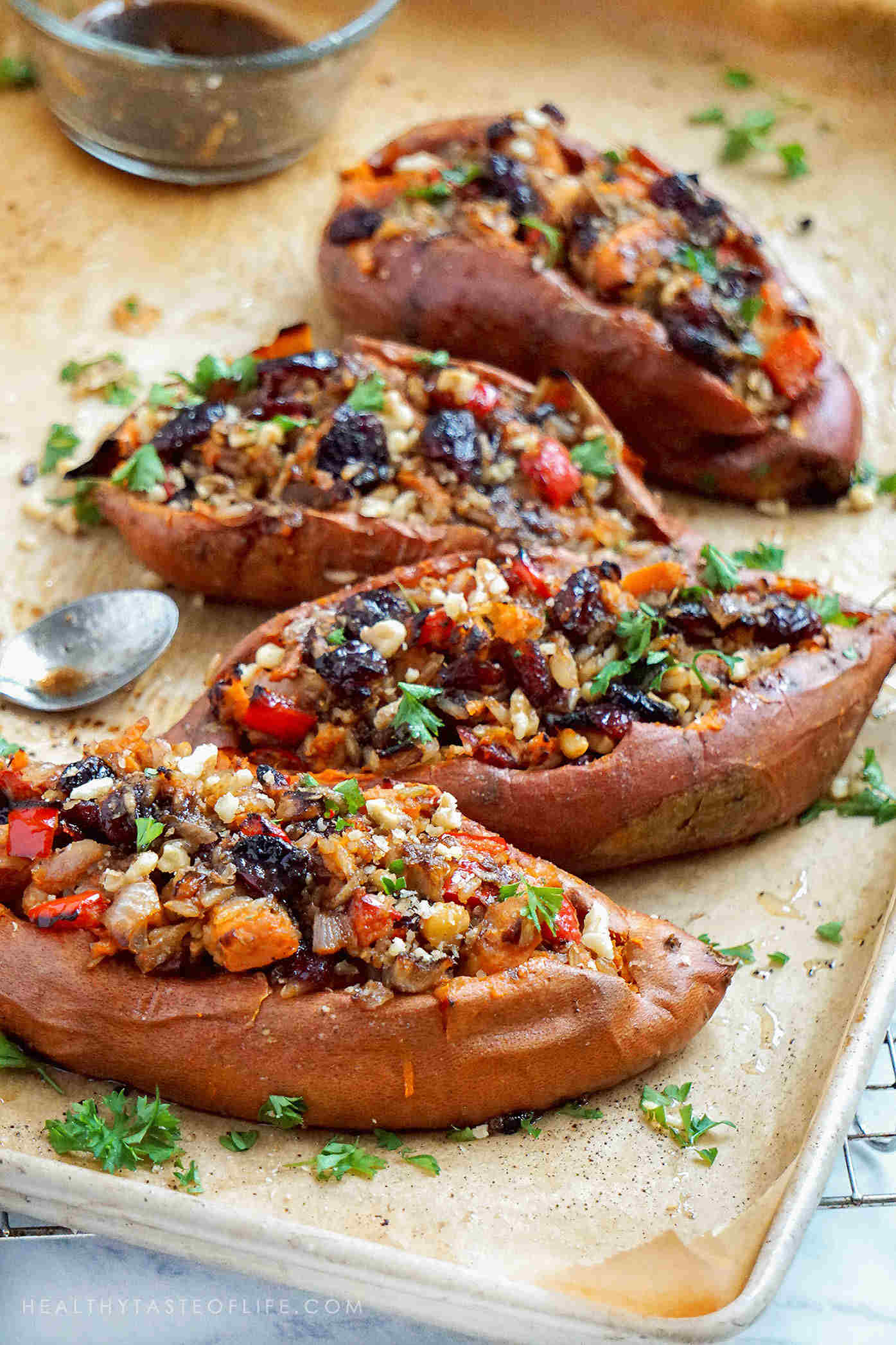 Close up shot of savory loaded Sweet Potatoes stuffed with rice, vegetables and dried fruits - baked in the oven and finished with a maple balsamic glaze.