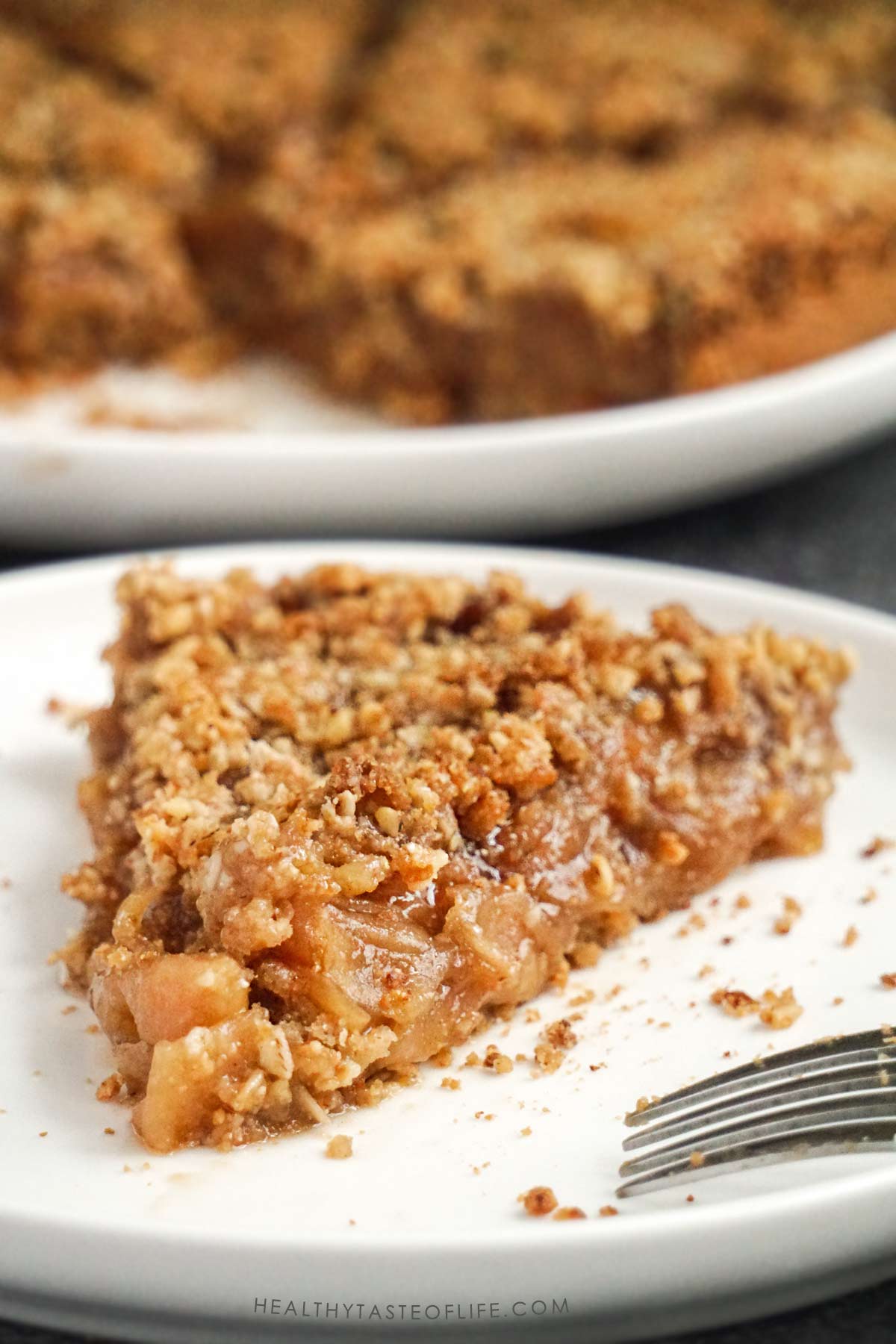 Slice of gluten free apple pie showing oat flour crust, juicy apple filling and crunchy cruble topping up close