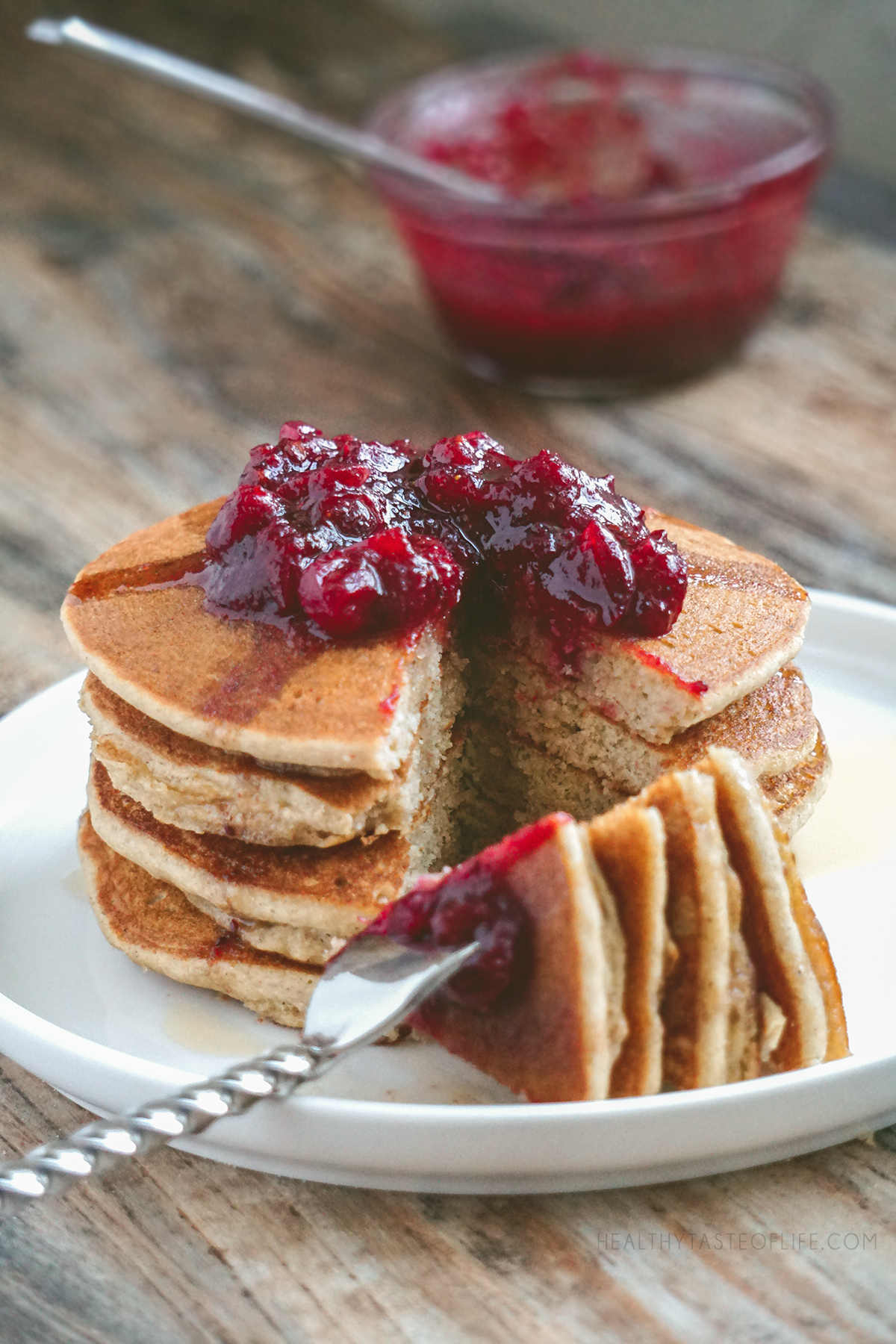 Stack of gluten free sourdough pancakes cut - fluffy soft inside, topped with a cranberry sauce.