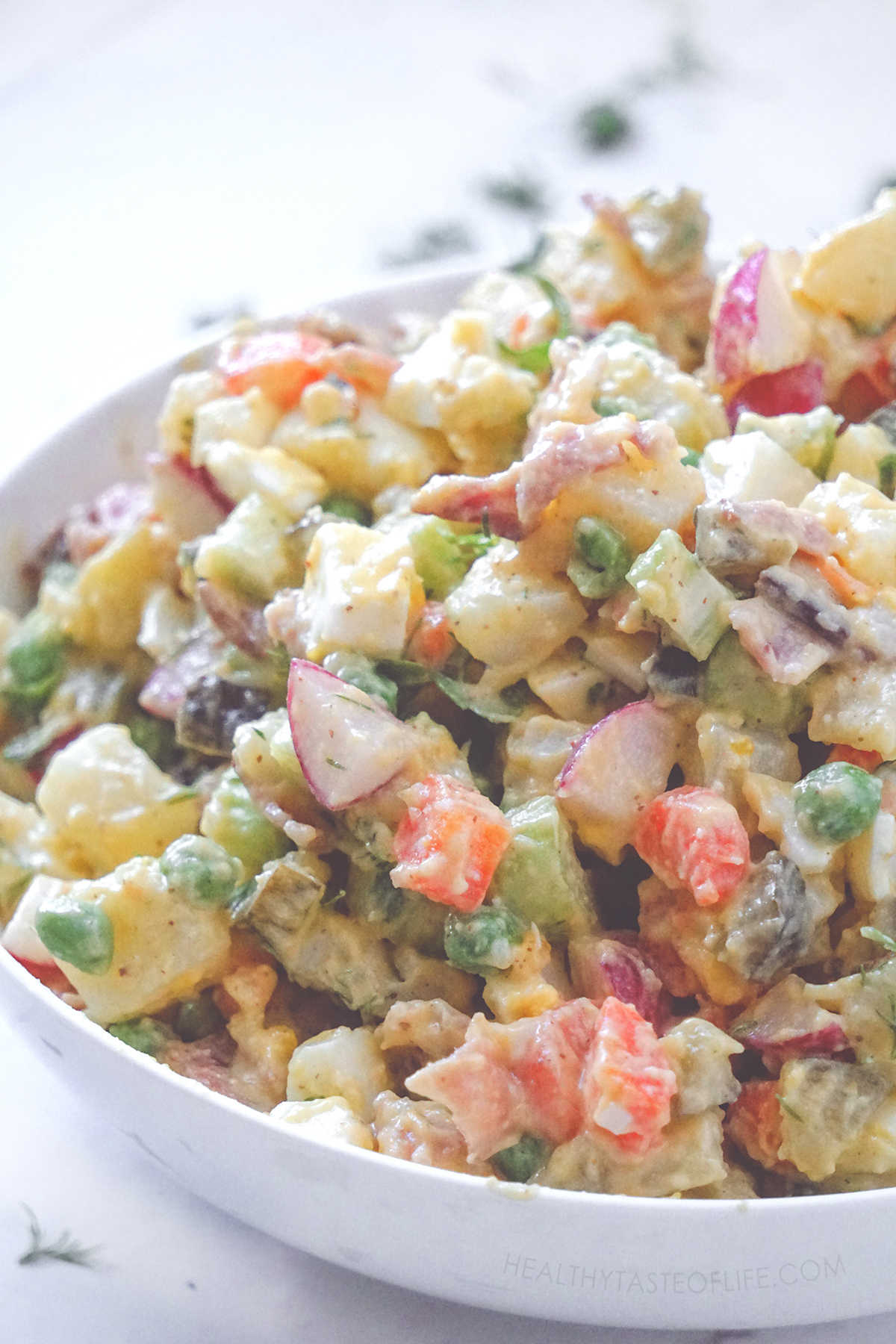 Potato salad made with cubed cooked potatoes, carrots, eggs, raw radishes, peas and celery, bacon (optional) with a creamy mayo free dressing. Similar To Olivier salad.