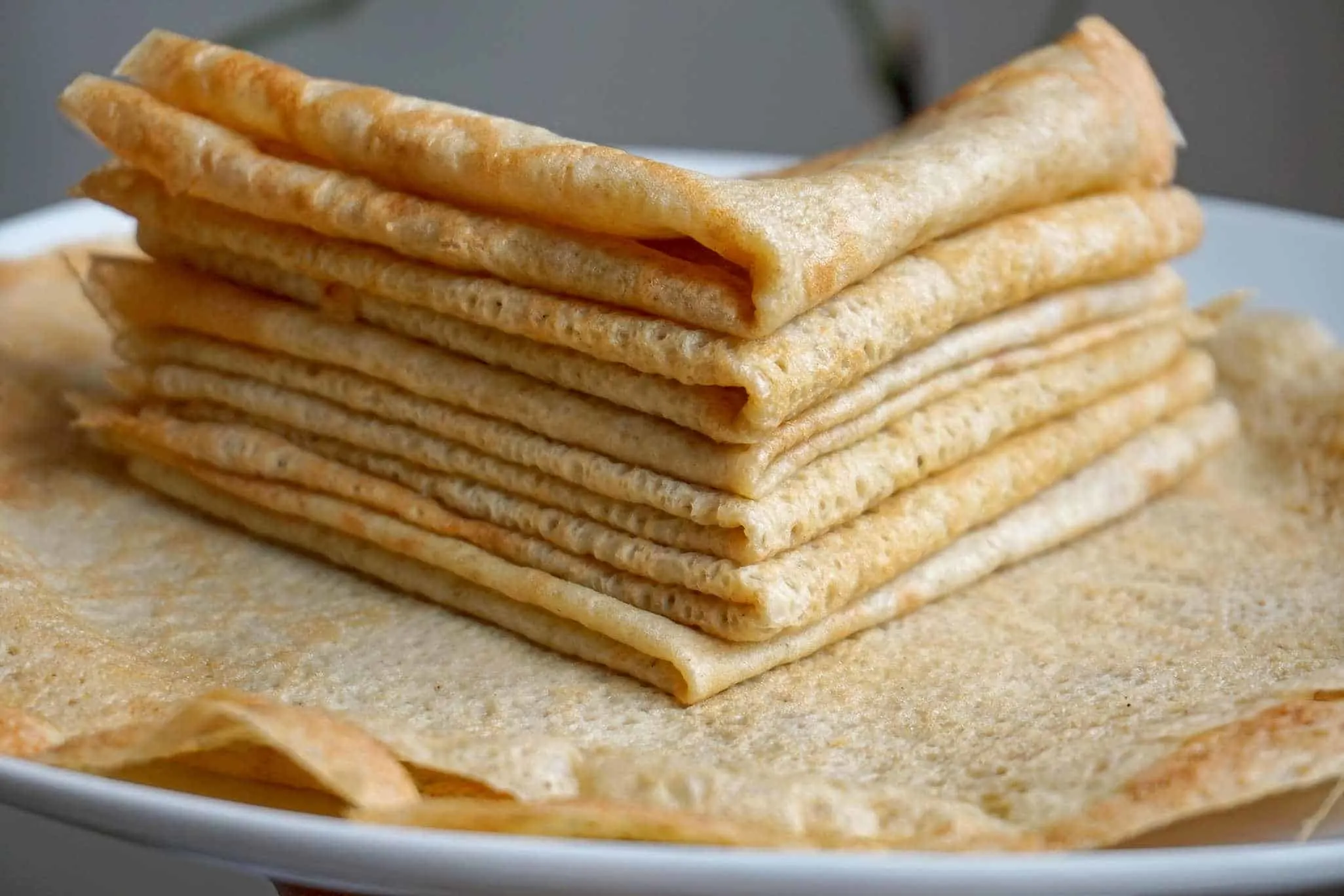 Dairy free gluten free crepes folded and stacked on a plate.