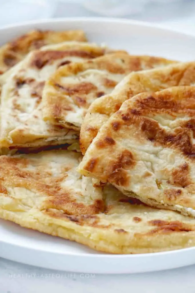 This homemade stuffed flatbread recipe makes crisp as well as soft golden brown flatbread stuffed with potato (vegan option), cheese filling or sweet filling (apples and sour cherries). No yeast, easy stuffed flatbread - great served as an appetizer with dips, make ahead finger food, or as a side dish along with your favorite dinner or lunch. The perfect party snack / appetizer for large crowds or family dinners. 