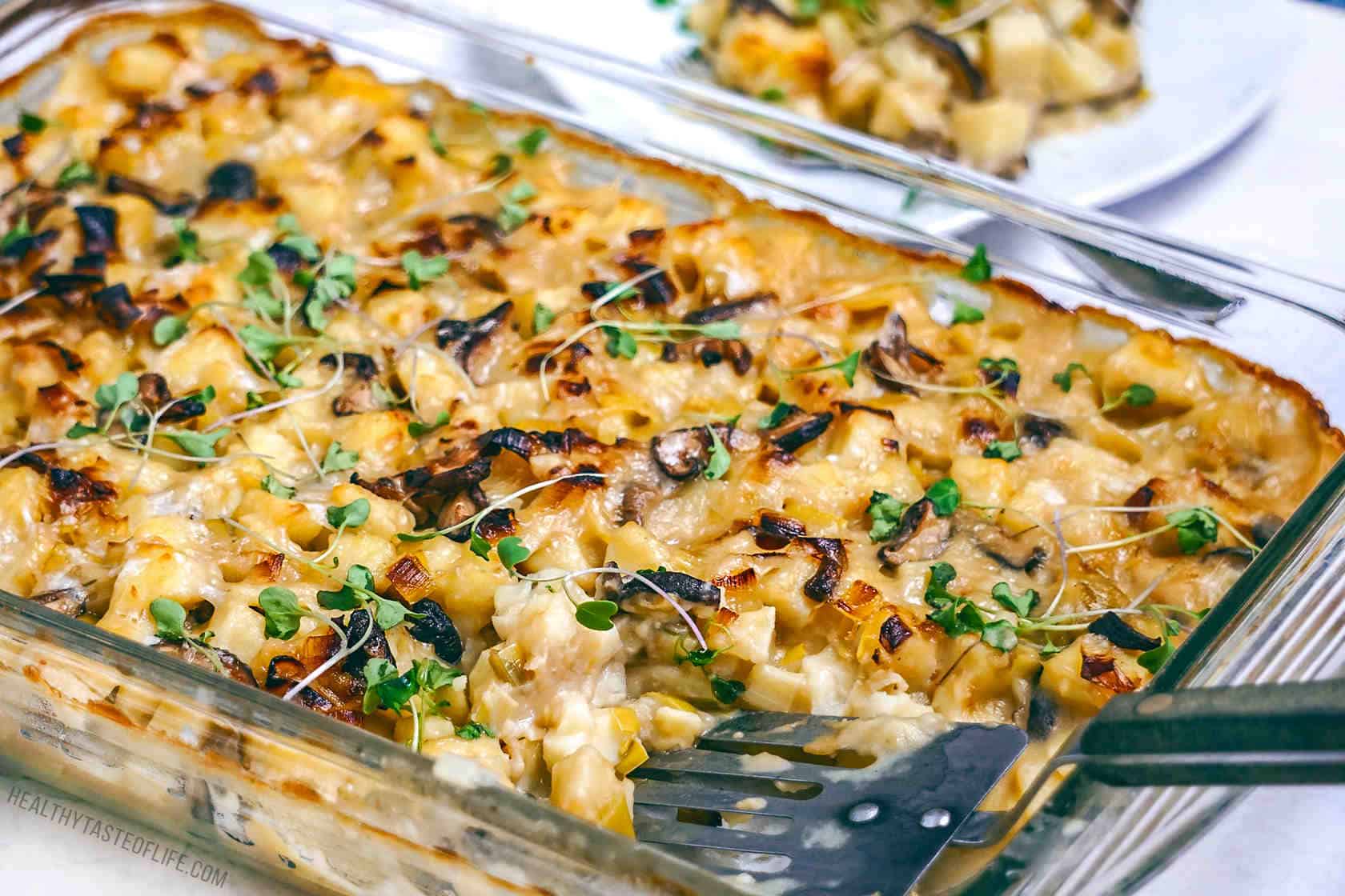 Vegan potato bake or casserole baked in the oven with a creamy vegan sauce, mushrooms and vegan feta cheese.