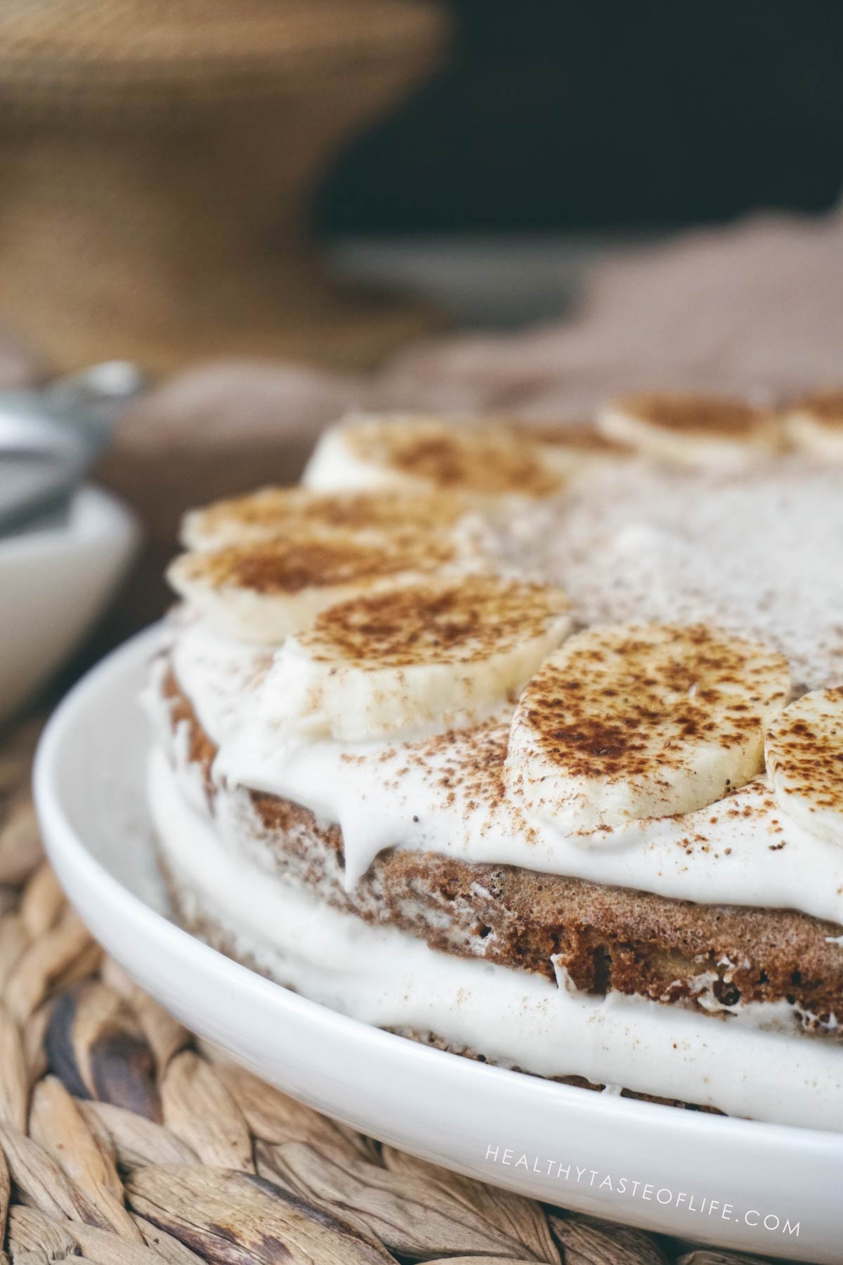 Gluten free banana cake with dairy free frosting assempled in 2 layers, topped with fresh banana slices.