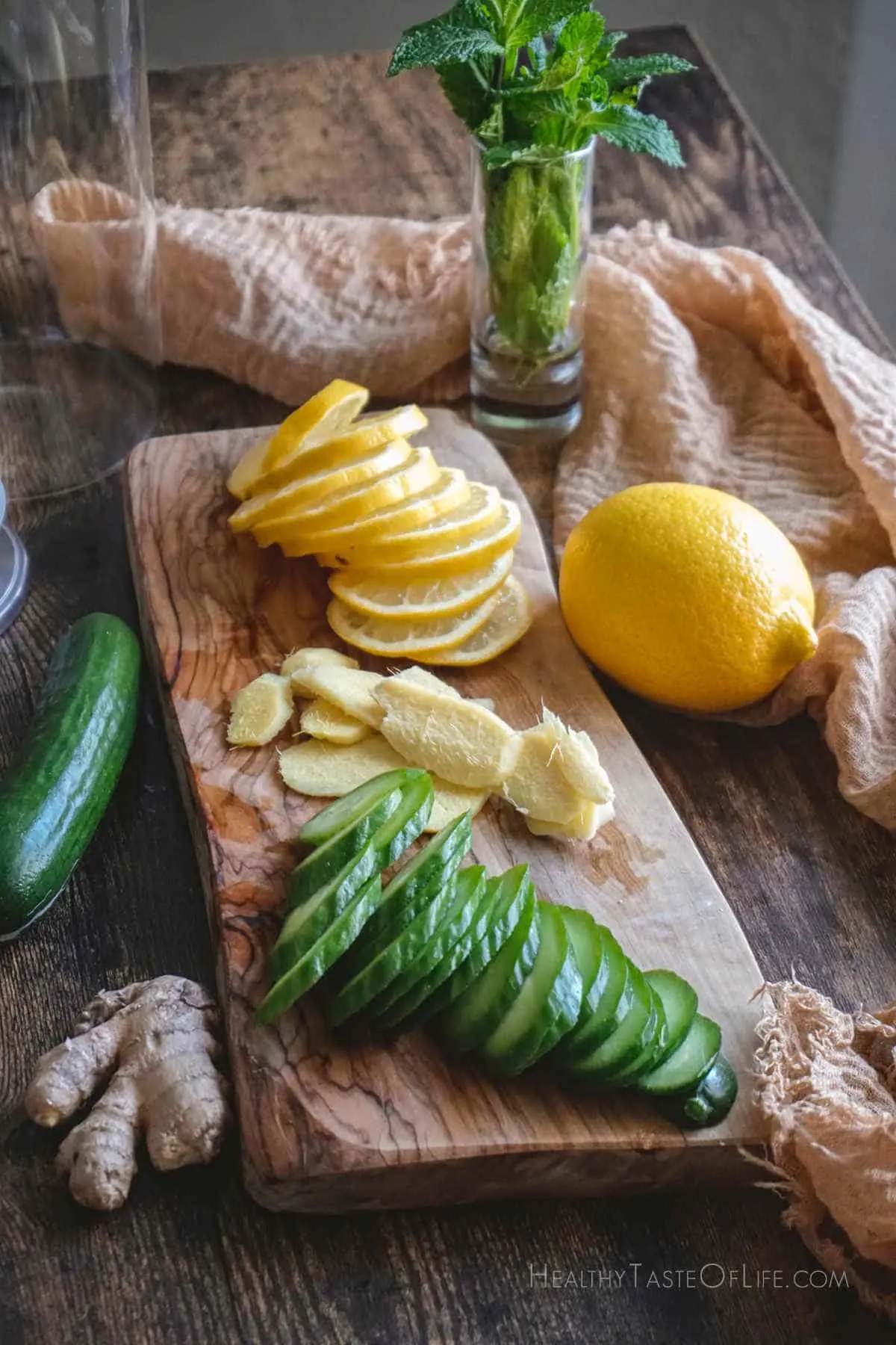 Picture showing the ingredients needed to make this cucumber lemon ginger water - all displayed ona board and cut into slices.