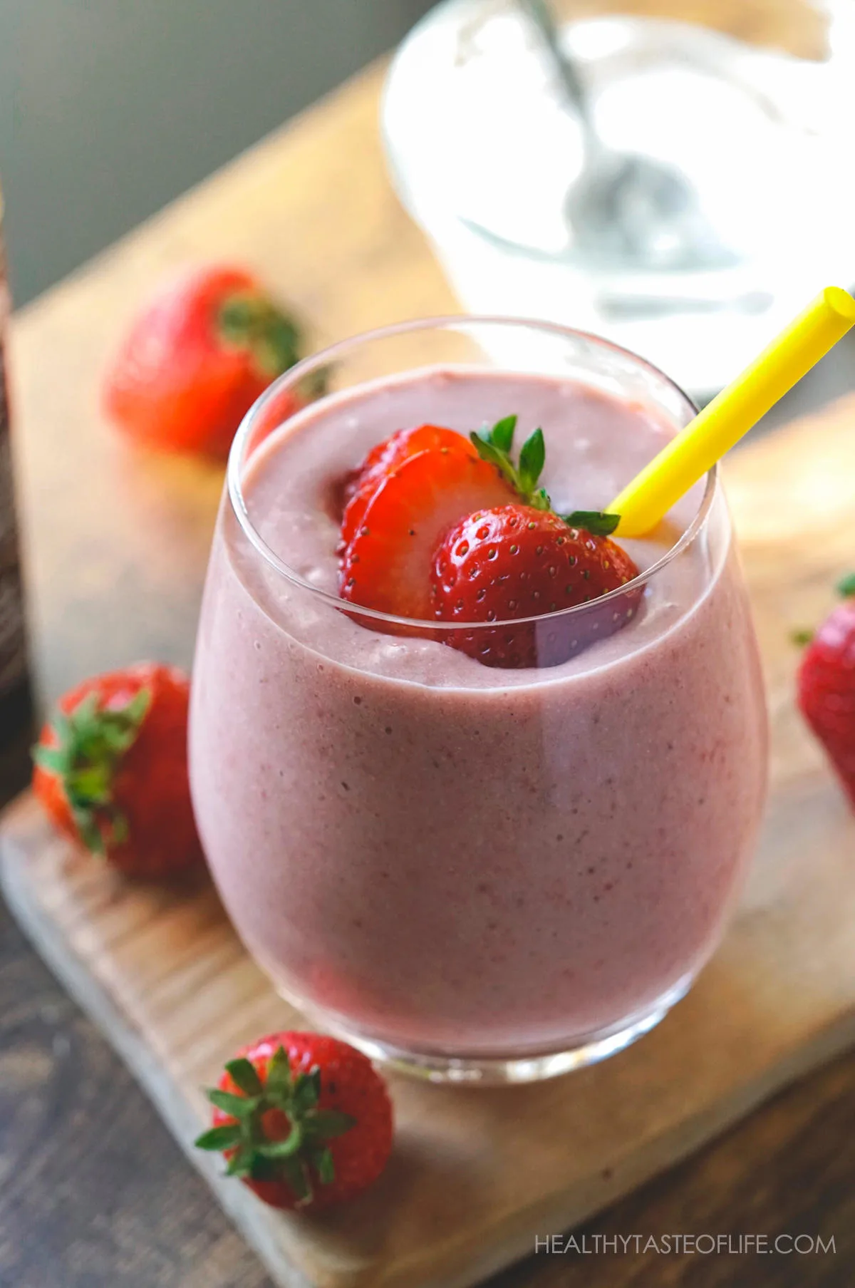 Strawberry and banana milkshake in a glass with a sliced strawberry and a straw.