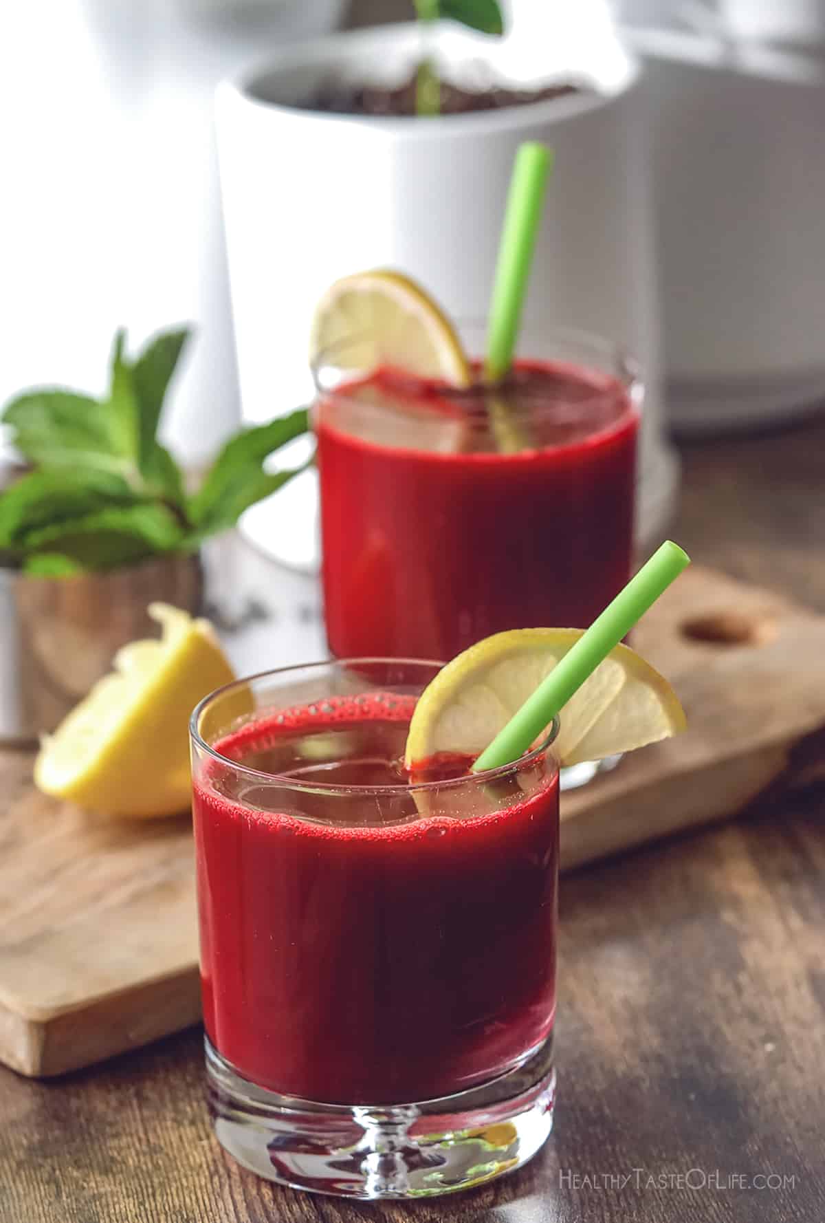 Freshly juiced beetroot juice served in a glass with a lemon wedge and a straw.