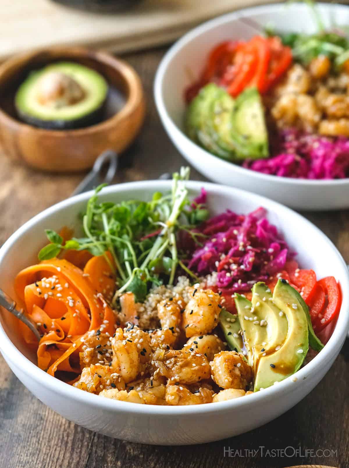 Quinoa poke bowl with shrimp and rainbow colors: carrots, bell peppers, avocado, sauerkraut, sprouts and poke sauce.