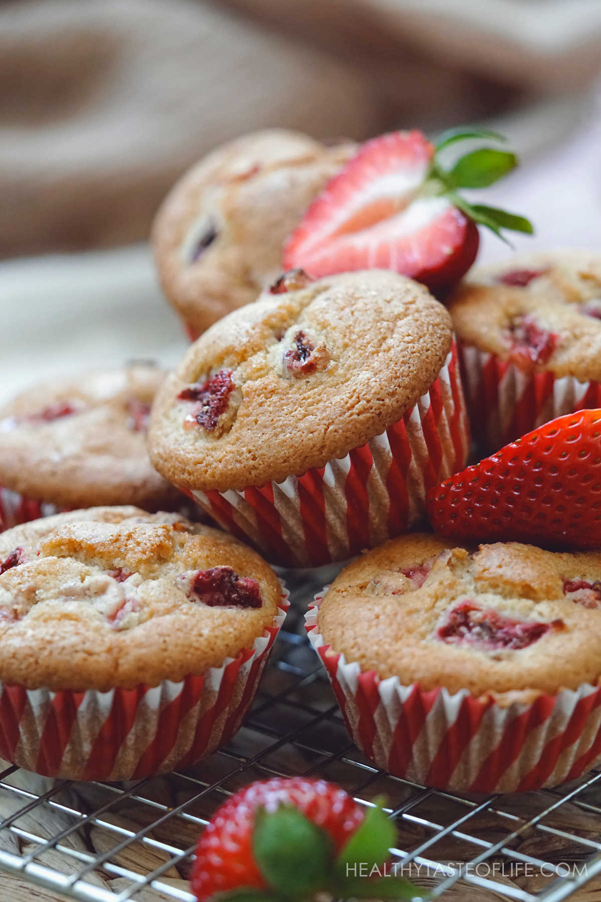 Strawberry muffins in red muffin liners decorated with strawberries.