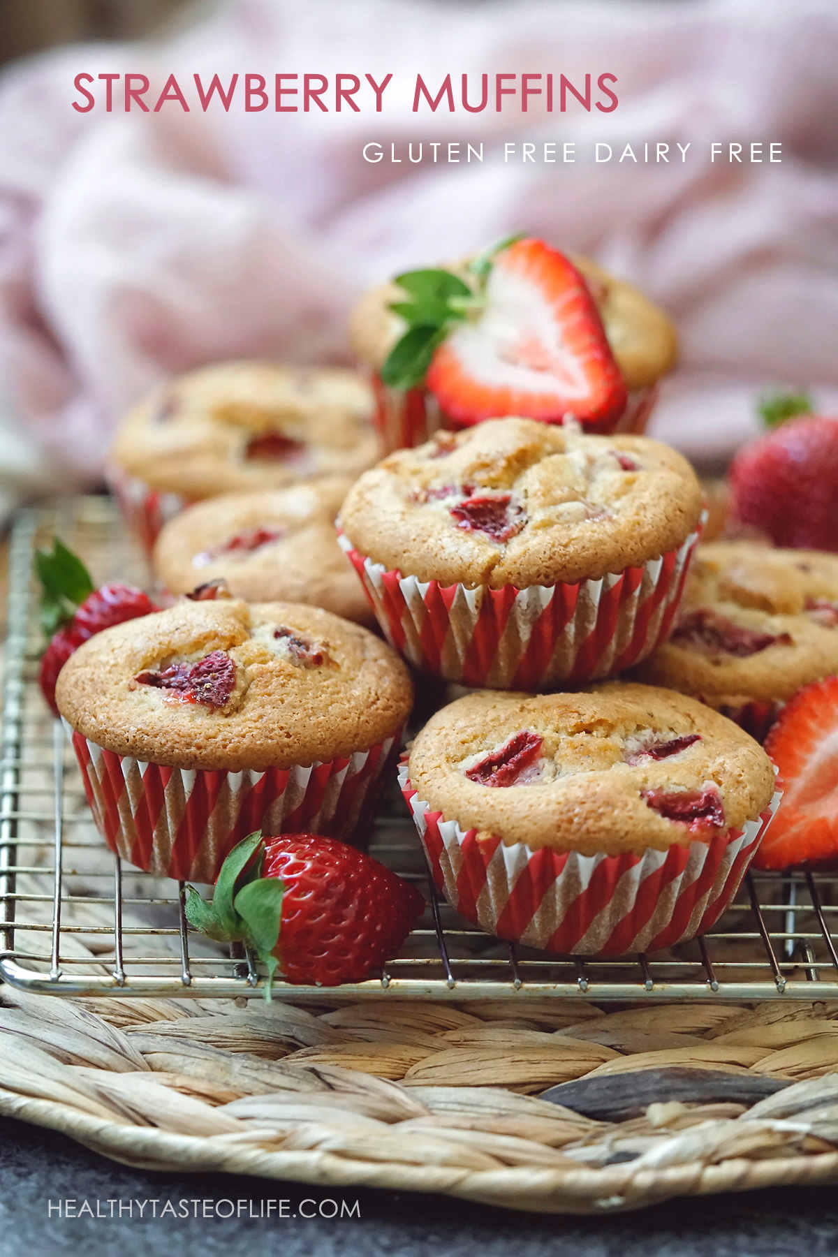 Strawberry muffins made with frozen strawberries stacked on rack and decorated with fresh strawberries.
