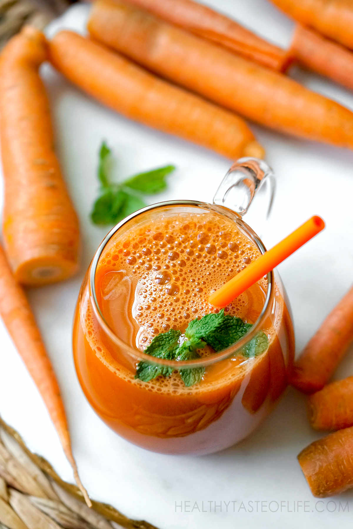 A glass mug filled with fresh carrot juice made with a juicer and blender. Homemade carrot juice recipe.
