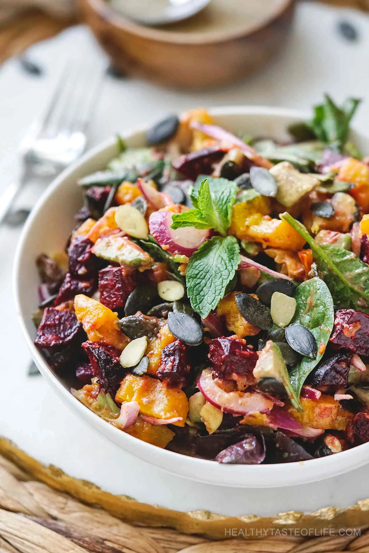 Close up on Pumpkin and Beetroot Salad with Pepitas in white bowl 