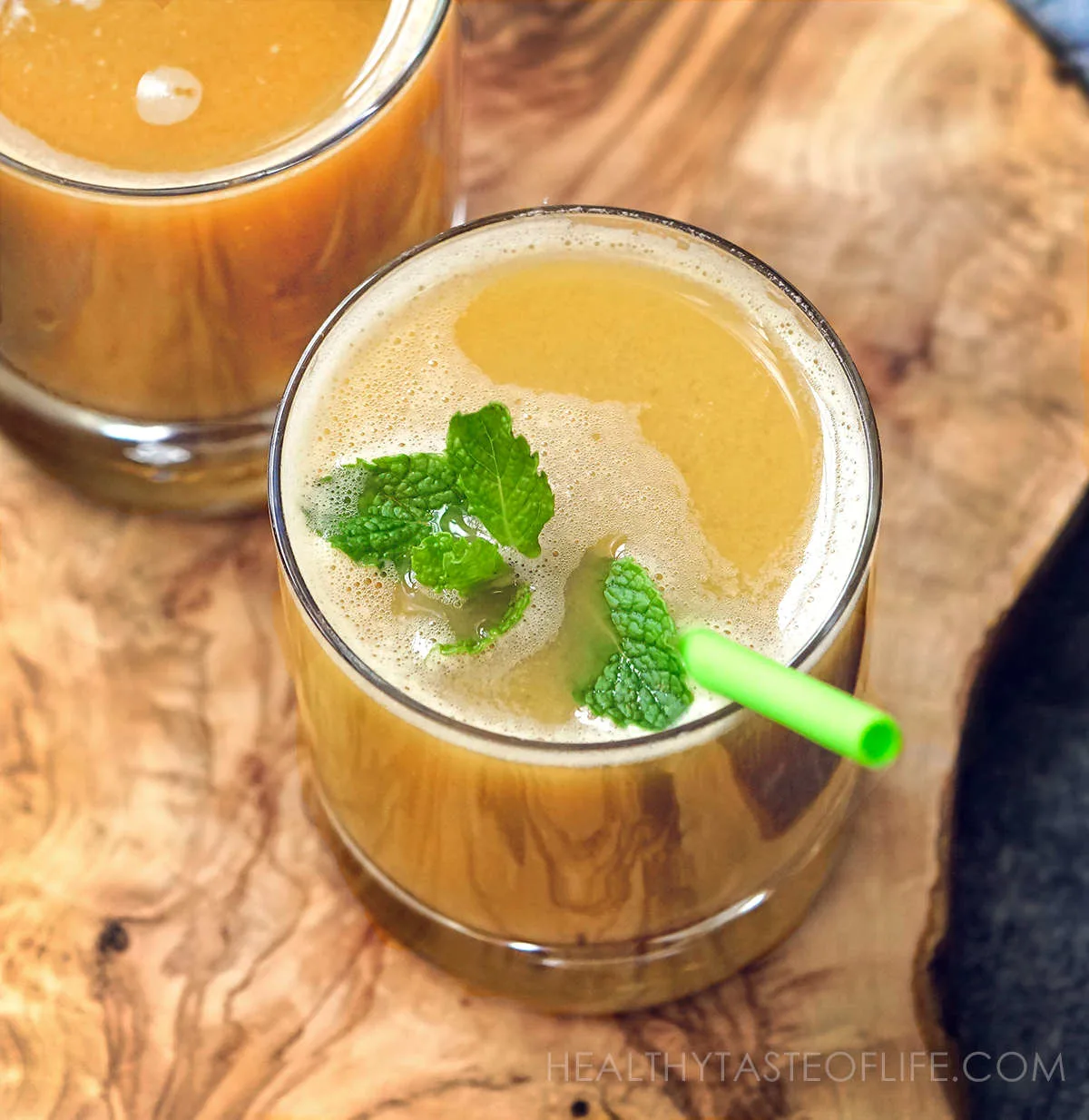 Cabbage juice in a glass garnished with mint leaves: raw cabbage juice with celery, carrot and apple.