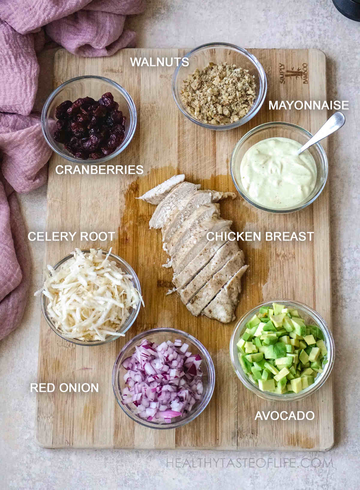 Ingredients for this cranberry walnut chicken salad - measured and displayed on a board: Chopped cooked chicken breast, walnuts, dried cranberries, onion, celery root, avocado and mayo.