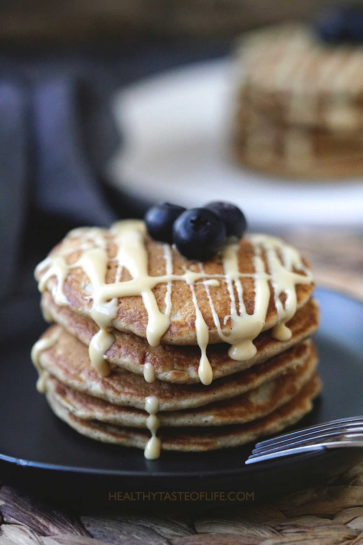 Stack of oat flour pancakes garnished with blueberries and maple cream.