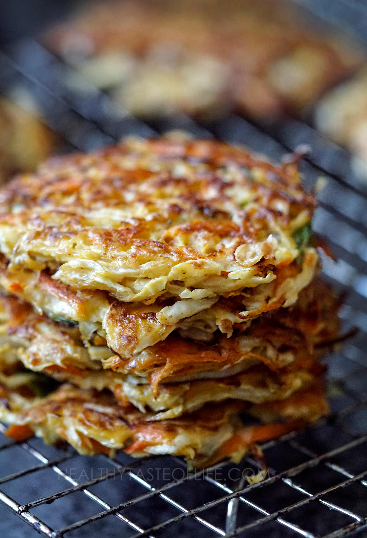 Cabbage fritters stacked on a wire rack.