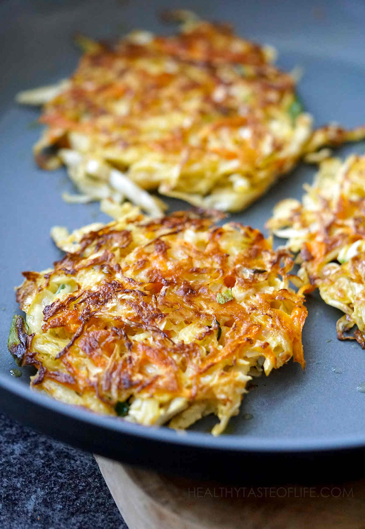 Fried cabbage fritters in a skillet.