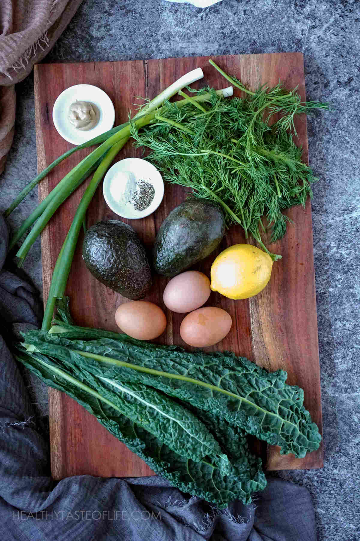 Ingredients for kale avocado salad  recipe displayed on a board.