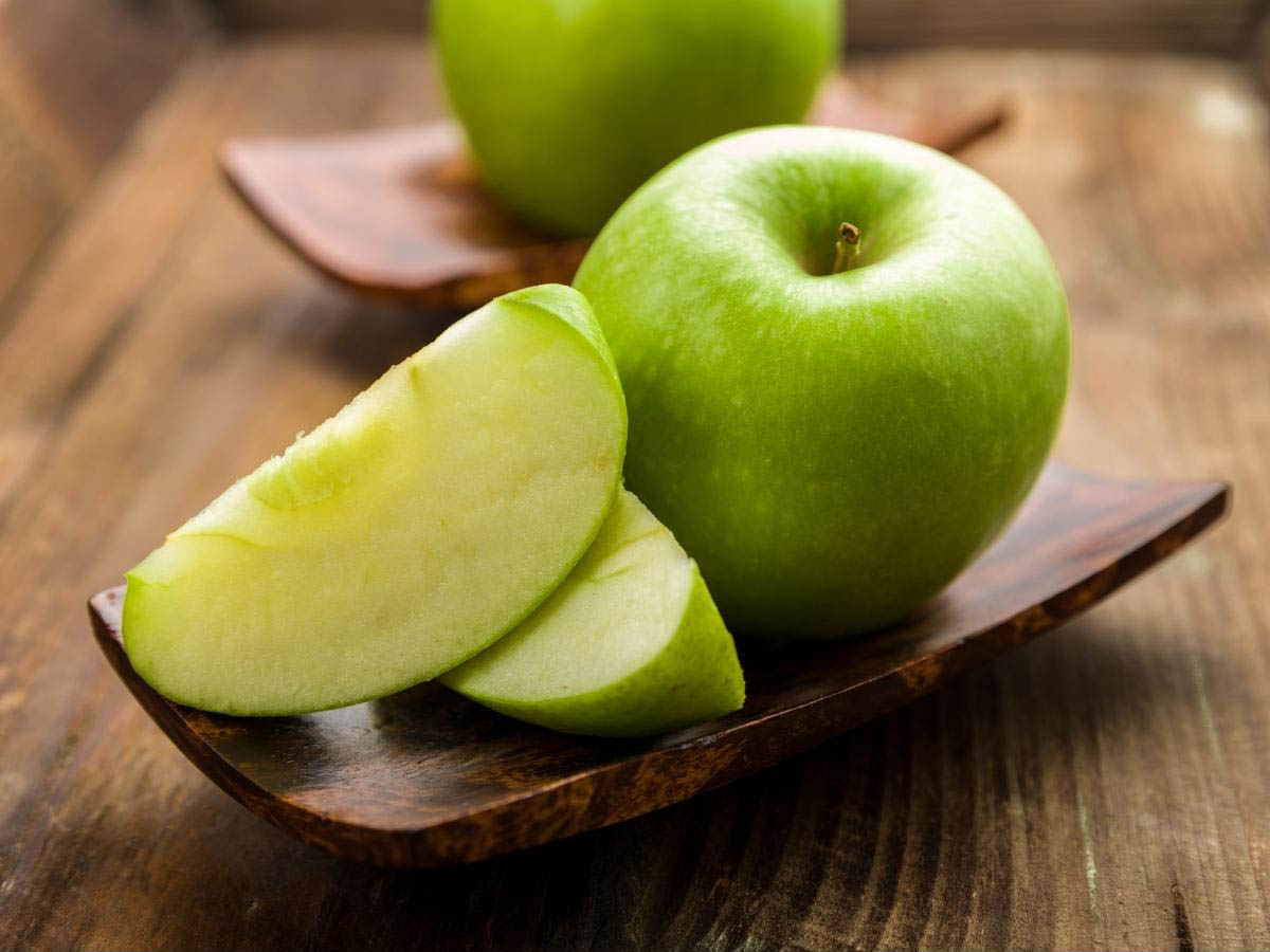 Green apple, cut on a board prepared for juicing.