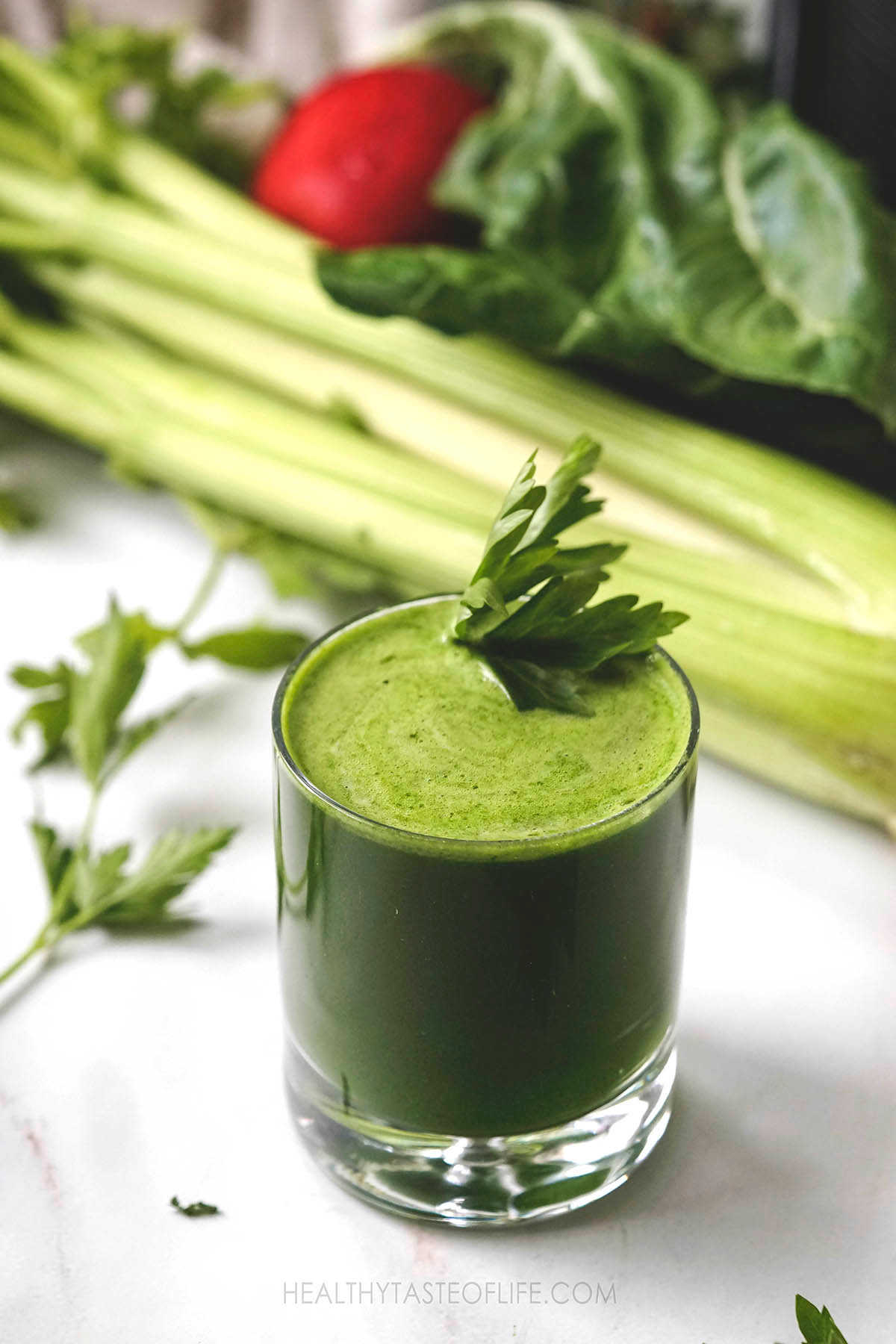 A glass filled with green anti-inflammatory juice and garnished with parsley.