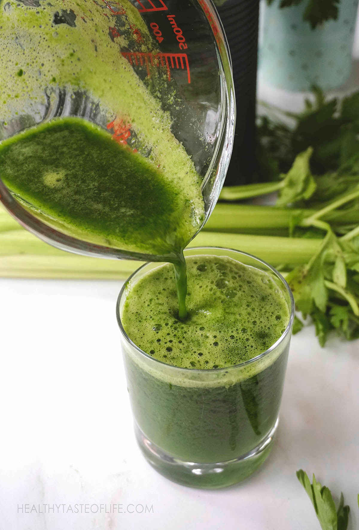 Pouring fresh green juice into a glass.
