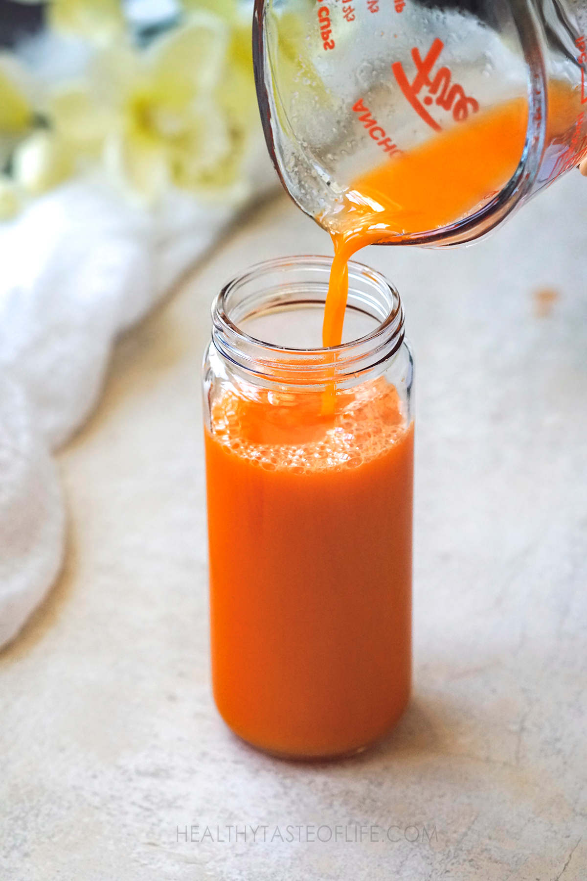 Pouring ginger carrot orange juice in a bottle.