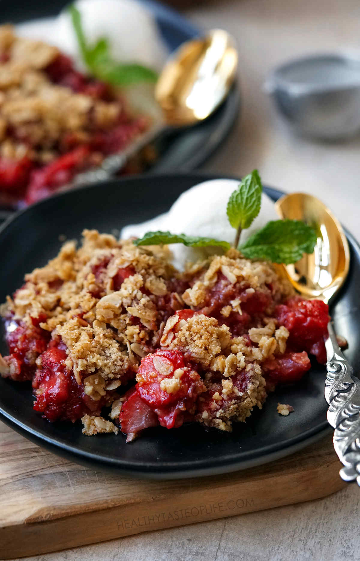 Strawberry crumble served with a scoop of vanilla ice cream and garnished with mint leaves.