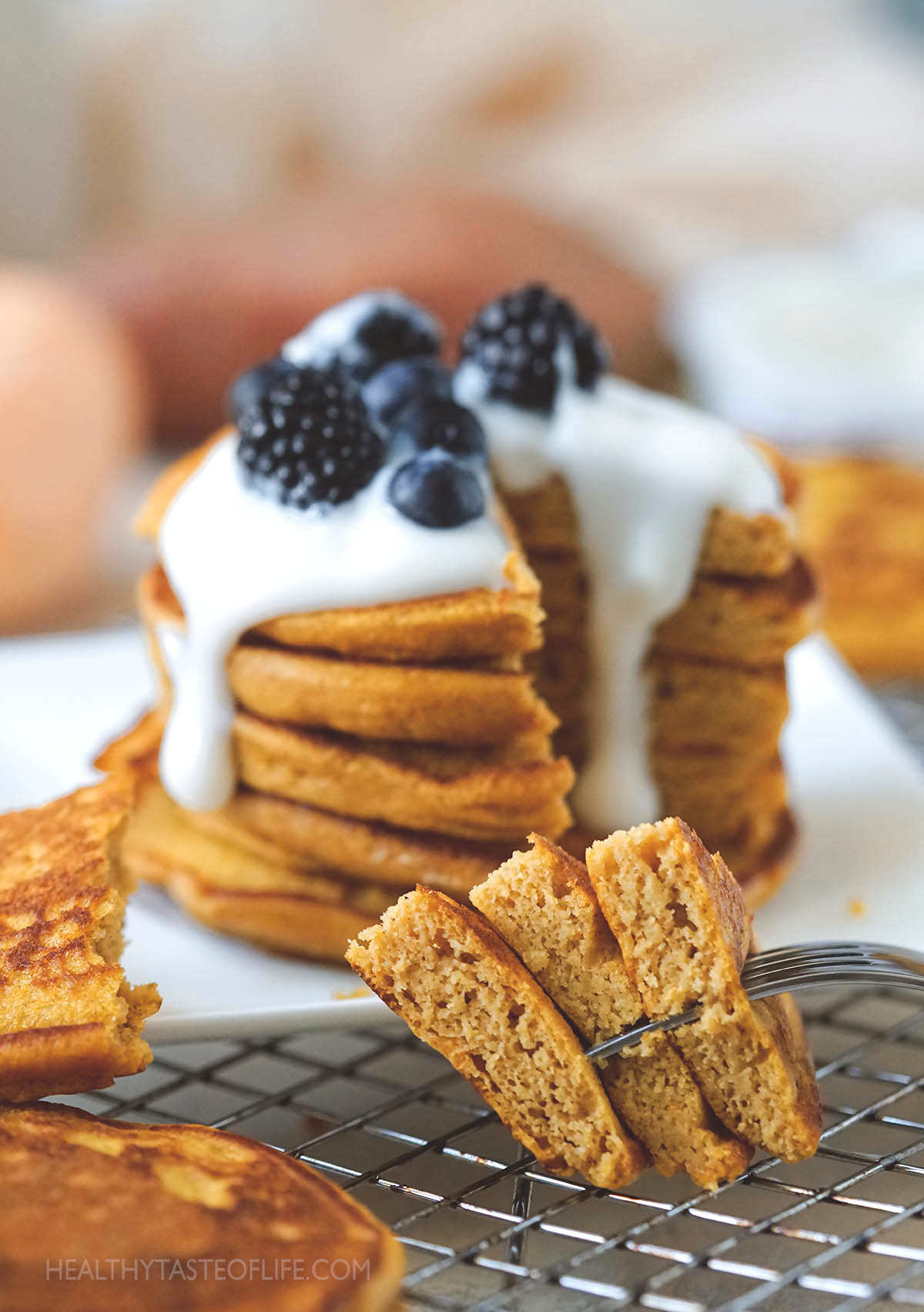 Stack of sweet potato pancakes topped with yogurt and fresh fruit.