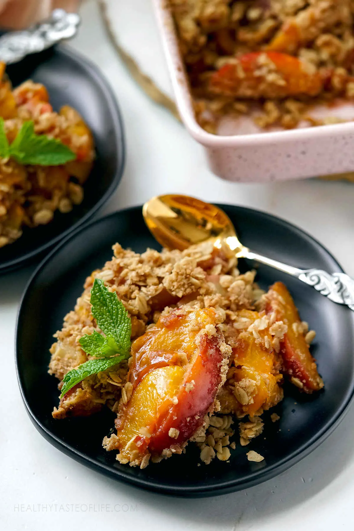Close up shot of peach crisp showing baked peach slices covered with crunchy oat topping.