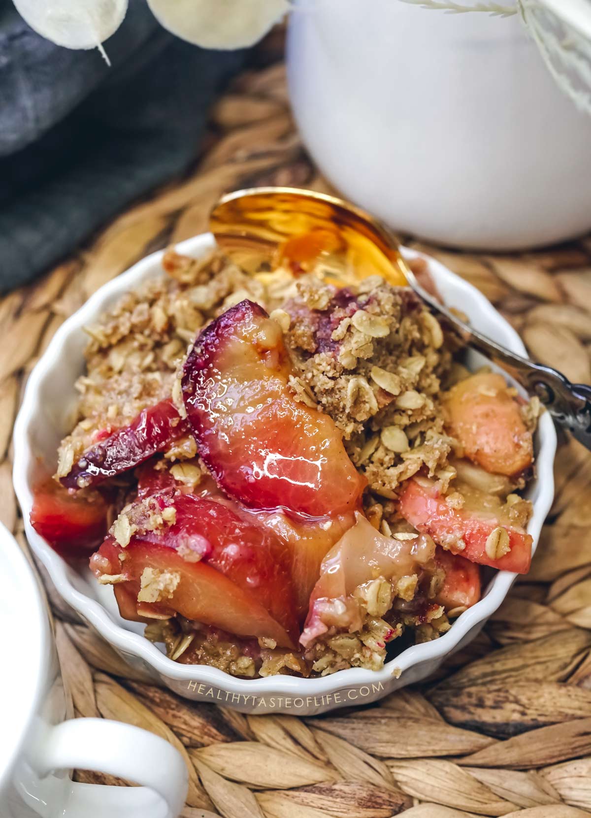 Apple plum crisp with jammy plums and crunchy oat topping served on a plate with ice cream