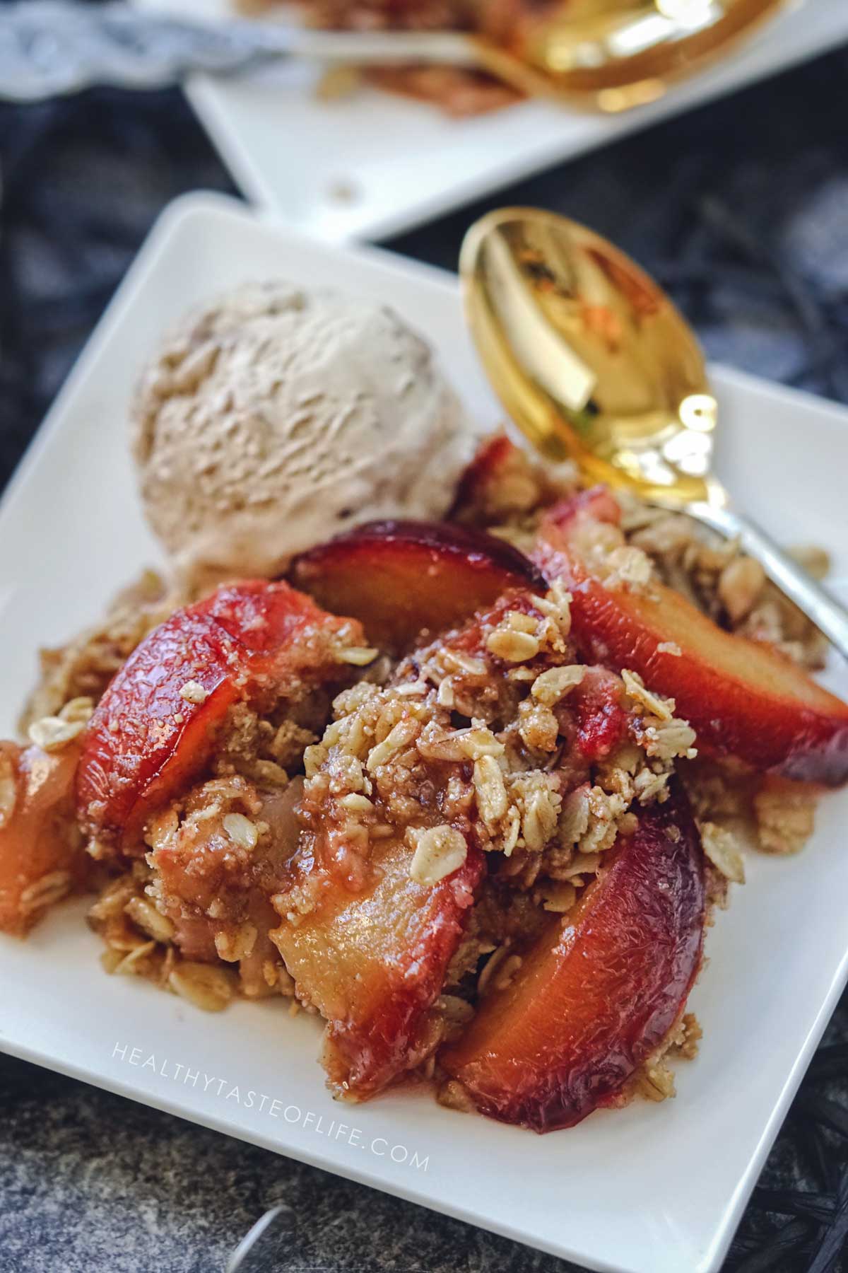 Serving of Apple plum crisp with oats and crunchy walnut topping close up