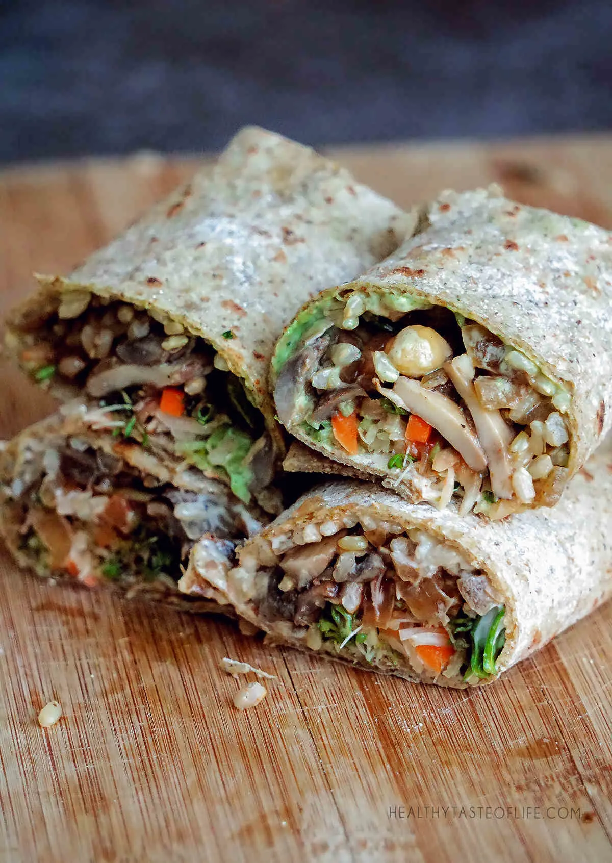 Savory breakfast burrito made with homemade gluten free tortillas filled with cooked mushrooms, rice, chickpeas, sauerkraut, greens and an avocado sauce.