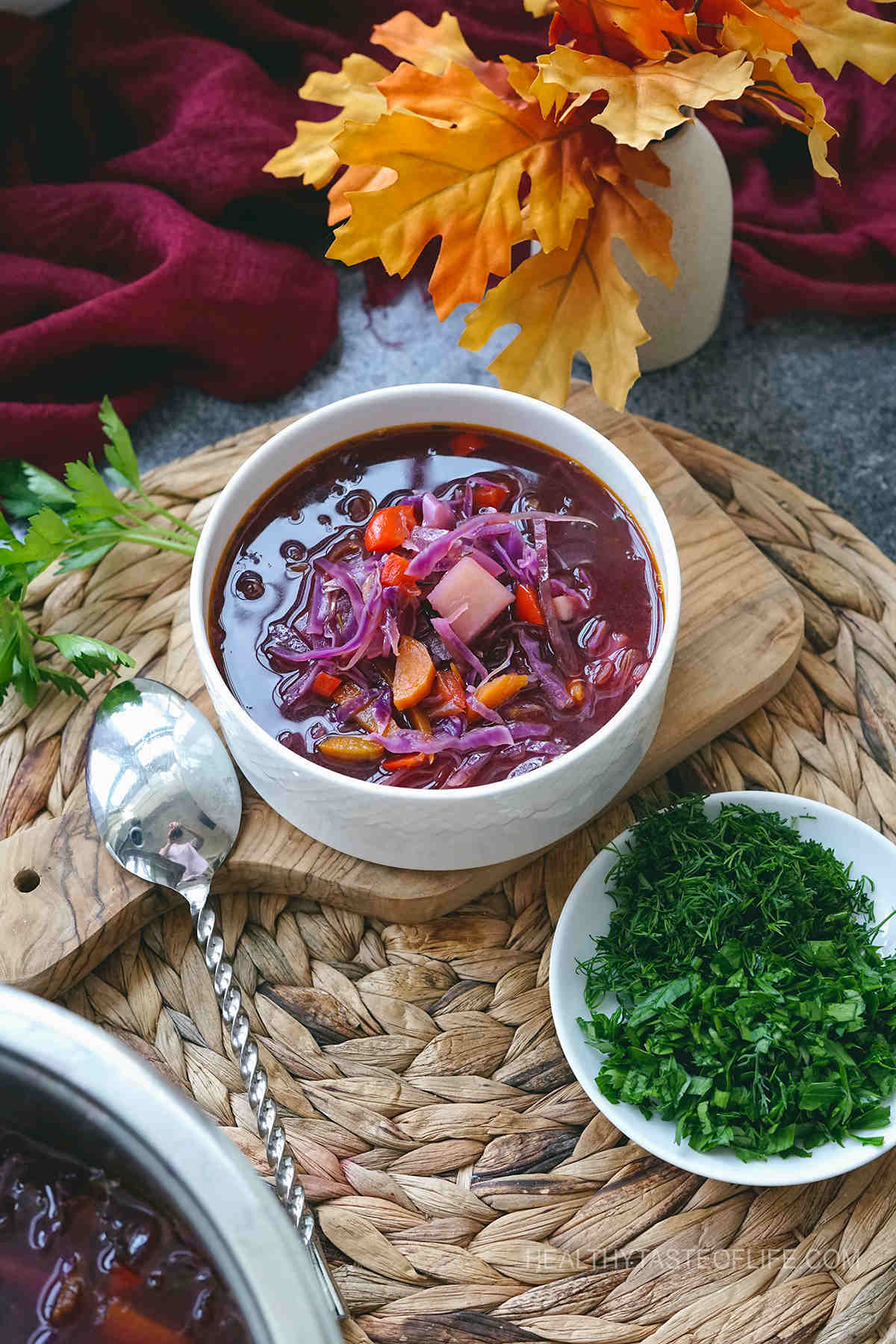 Ready to serve red cabbage soup with a side of fresh chopped herbs to top with.