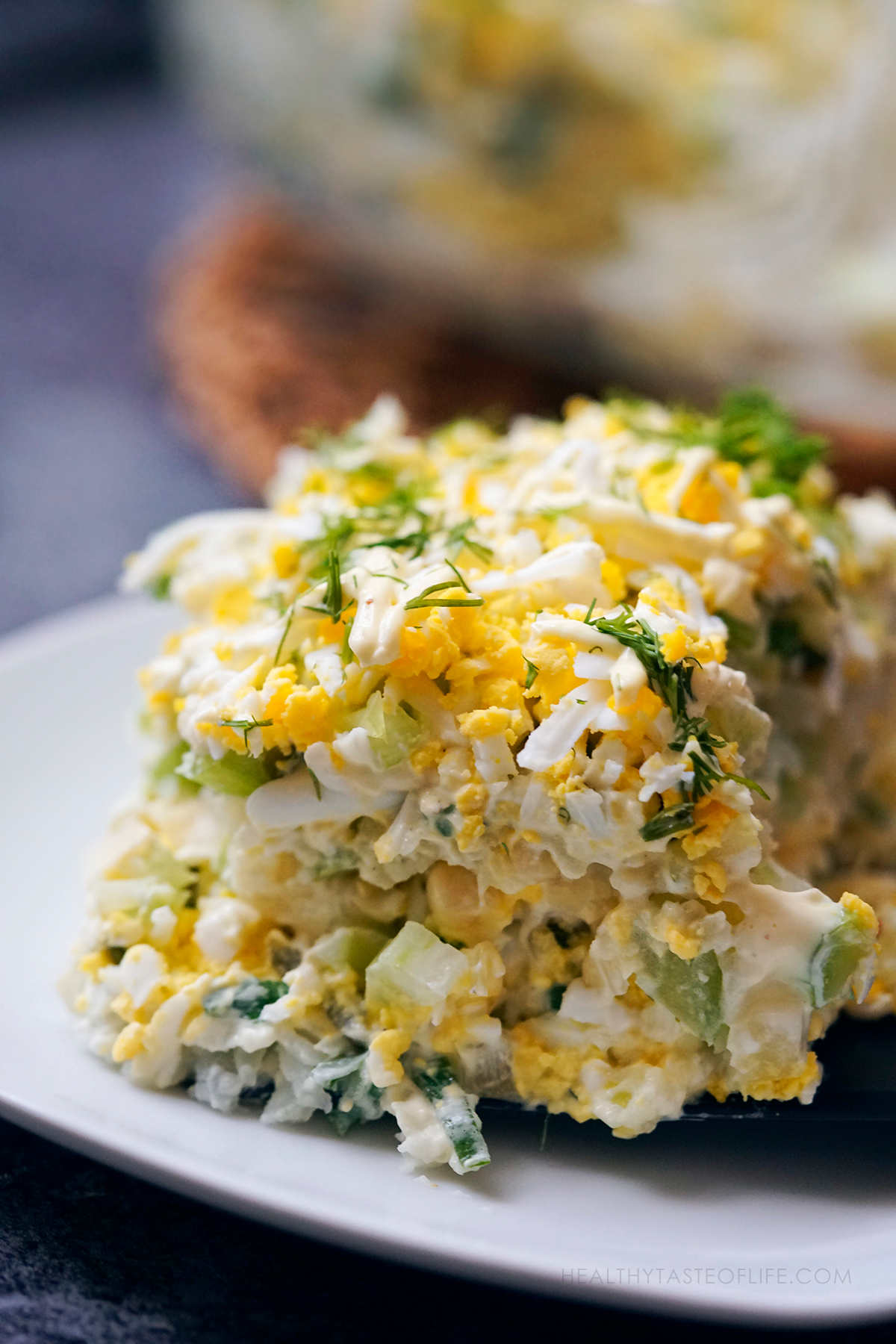 Close up shot of potato and egg salad assembled with mayo and arranged in layers, served cut with a spatula.