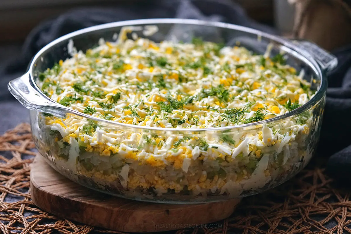 Assembled potato egg salad served in a round glass dish, perfect for holiday tables.