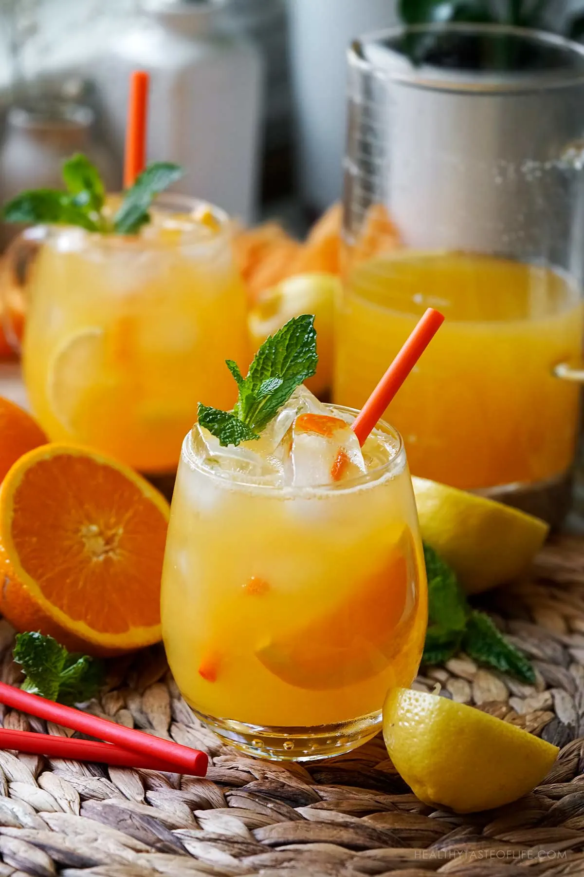 Orange lemonade aka orangeade served in glasses over ice and garnished with a slice of oarnge and lemon.