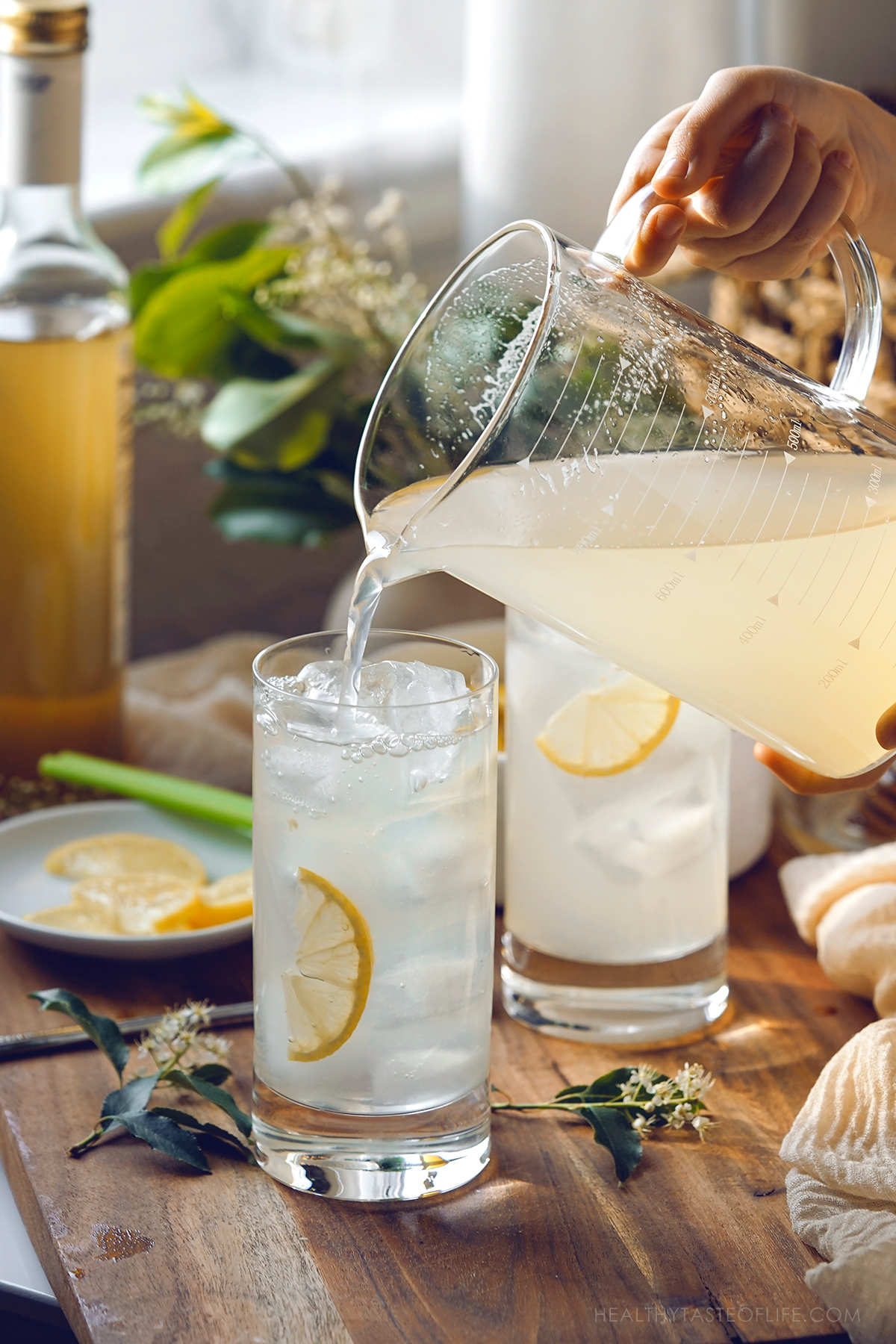 Photo showing the pouring of ready elederflower lemonade into serving glasses with ice.
