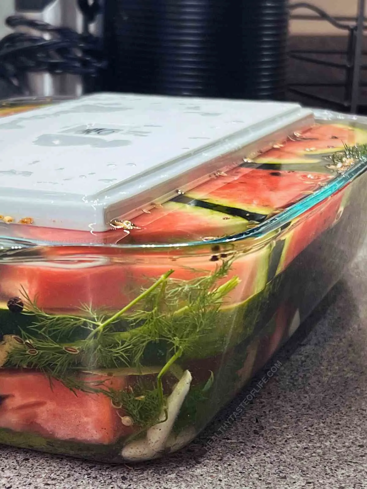 Picture showing how the watermelon is submerged in the brine with a platter on top as weight.