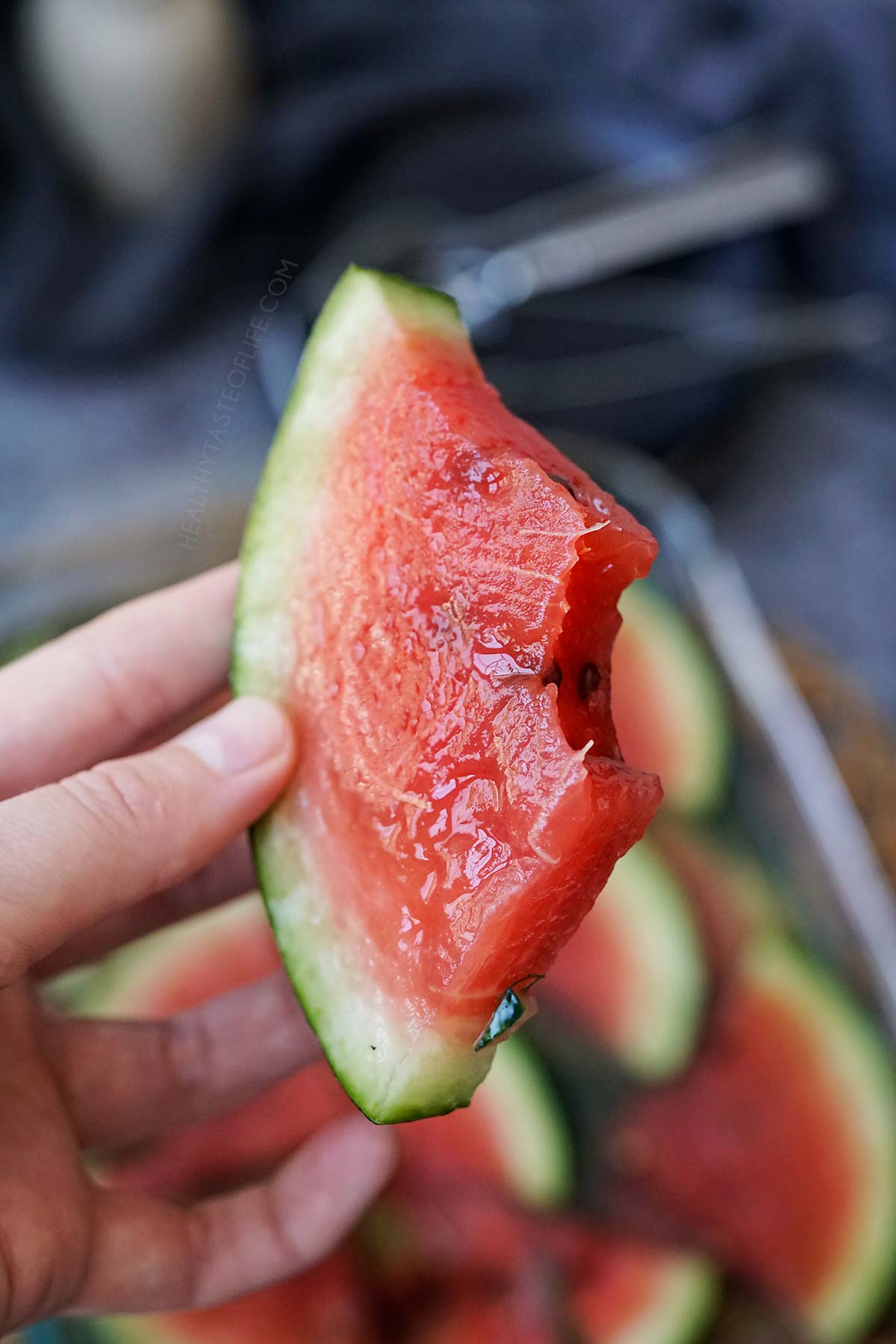 Bitten fermented watermelon slice held in my hand showing the texture inside.