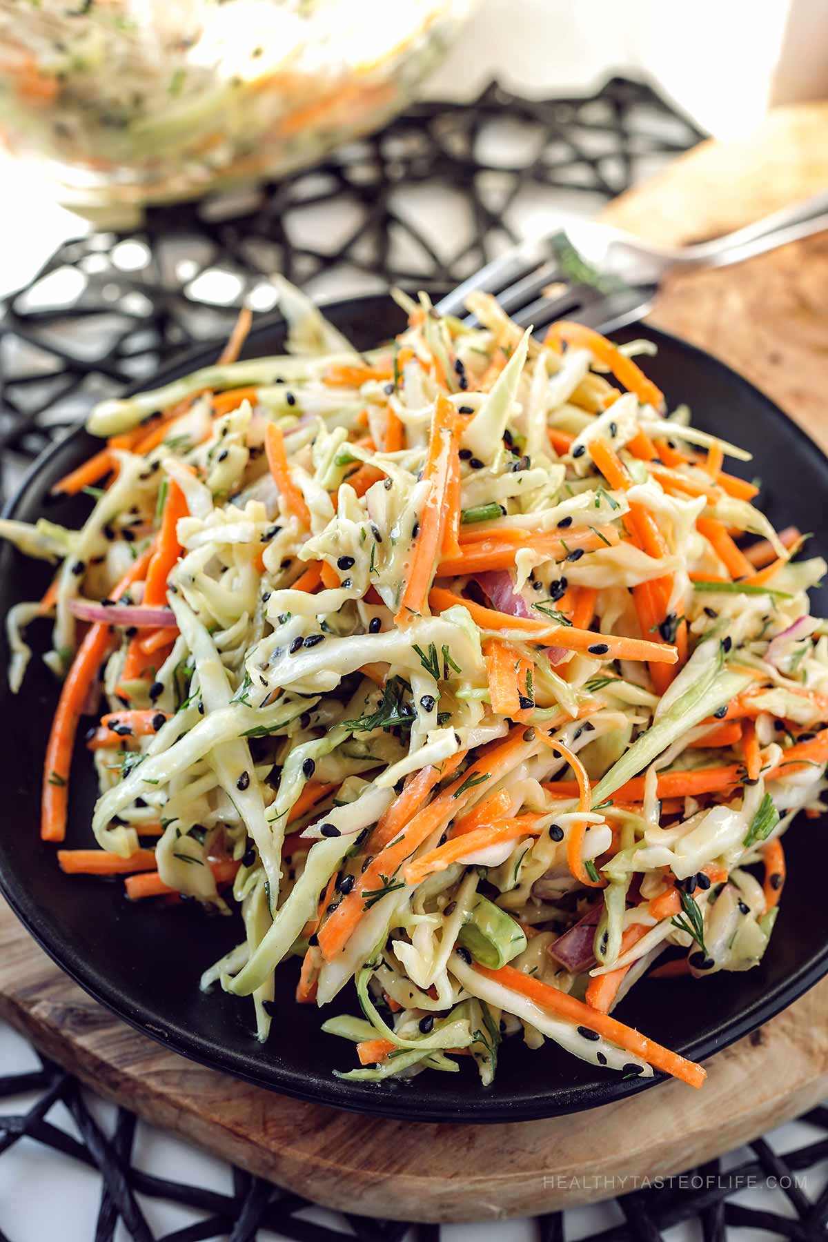 Cabbage and carrot salad served on a black plate.