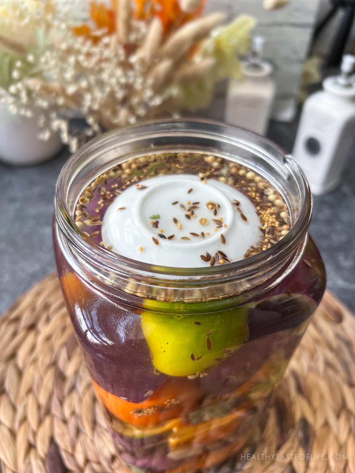 jar filled with peppers and tomatoes spices ready to ferment