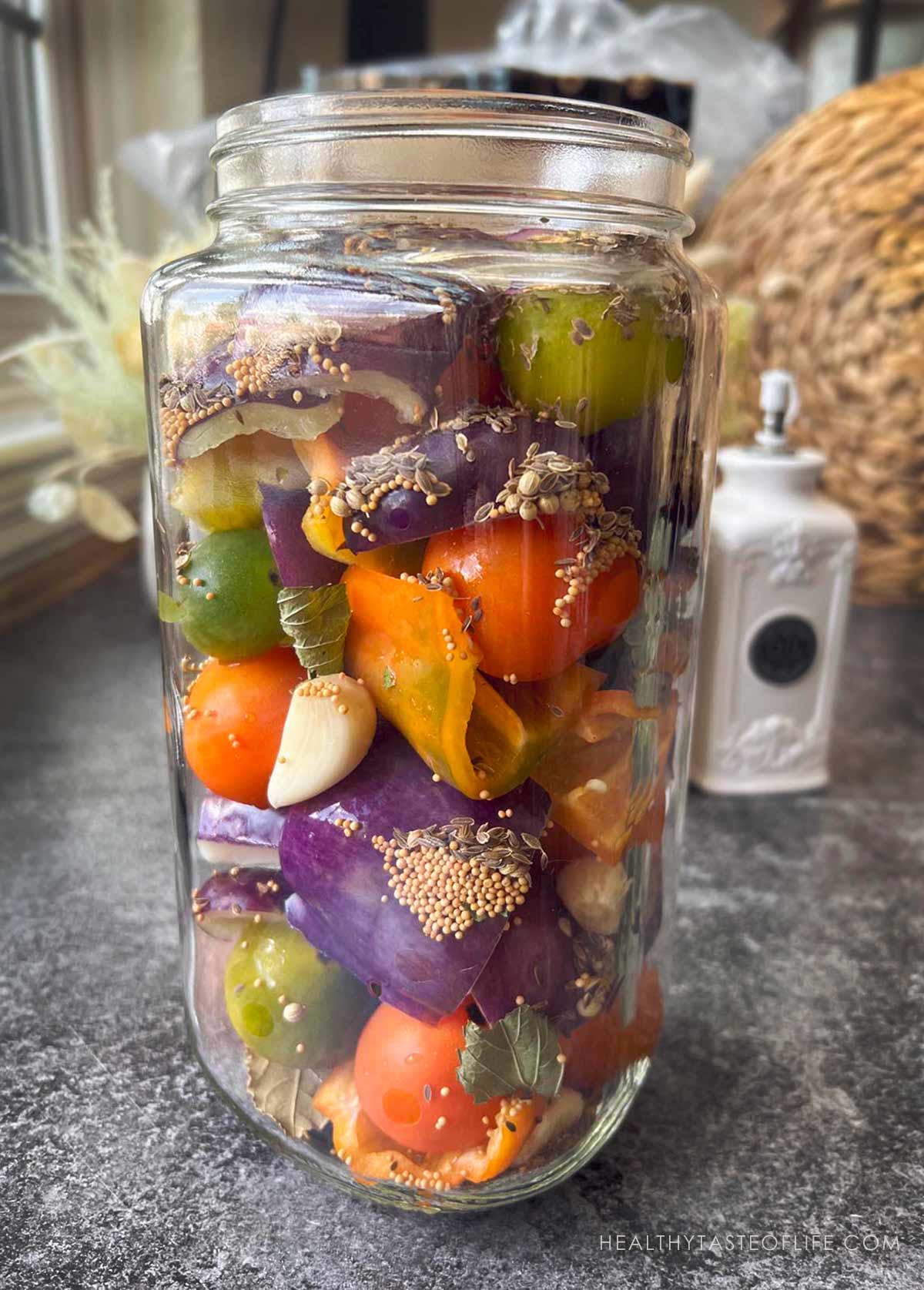 Peppers and tomatoes arranged in a jar for pickling.