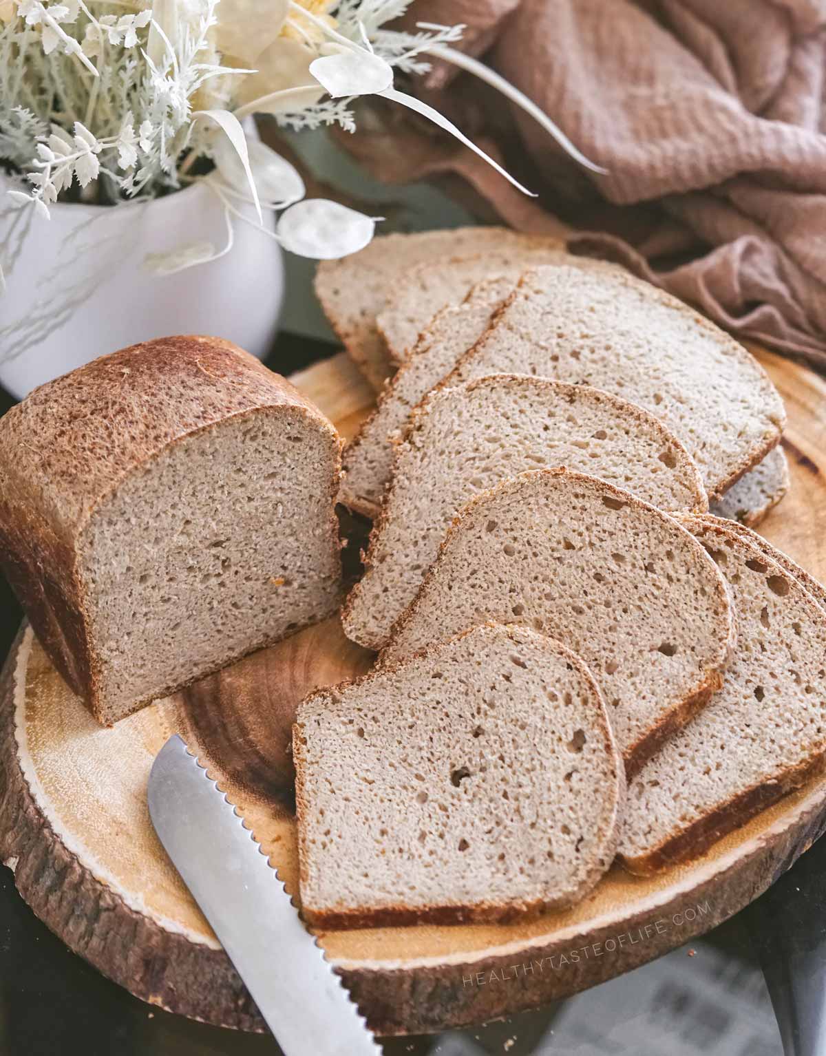 Gluten-free sourdough bread: thin slices on a wooden board holding together without crumbs, looking moist but not gummy