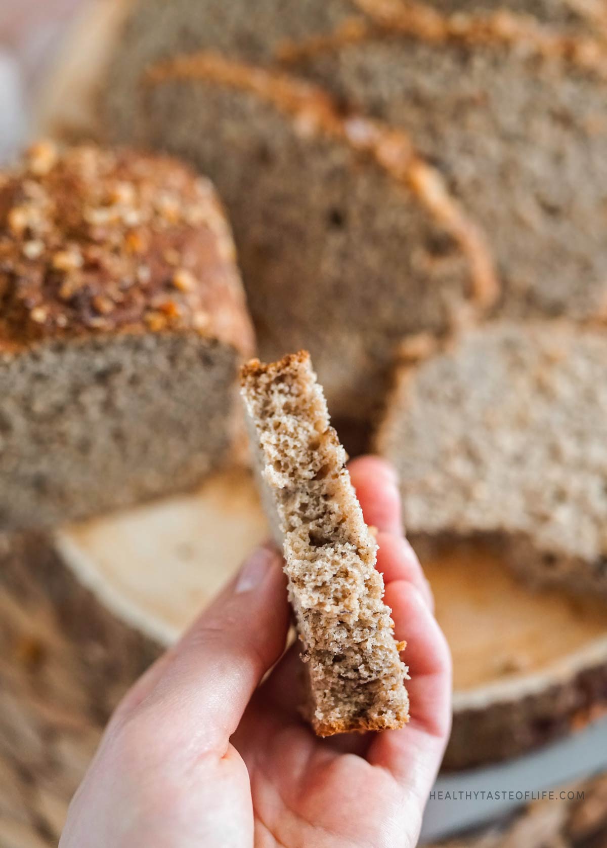 Holding a piece of banana bread showing soft and tender texture up close